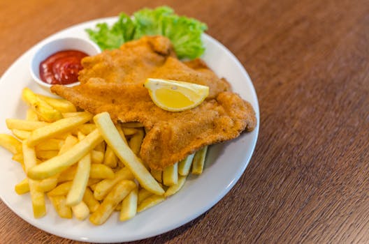 pexels photo 1352274 1352274 Delicious schnitzel served with crispy french fries, ketchup, and fresh lettuce on a plate.