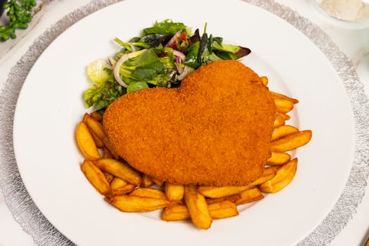 pexels photo 29042347 29042347 Delicious heart-shaped schnitzel served with crispy chips and fresh salad.